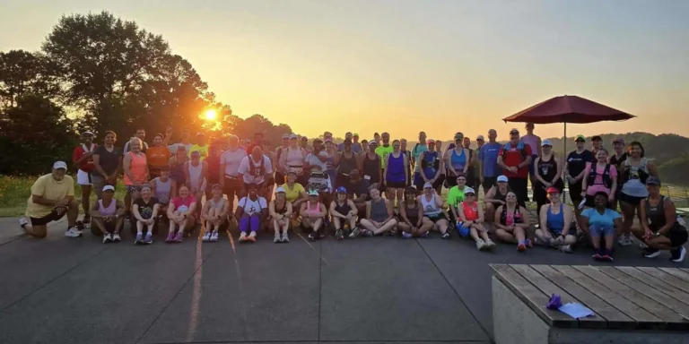 Group of runners at sunrise gathering outdoors.