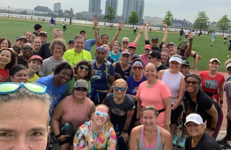 Large NYC local group of Run Walk Run runners posing together at an outdoor event