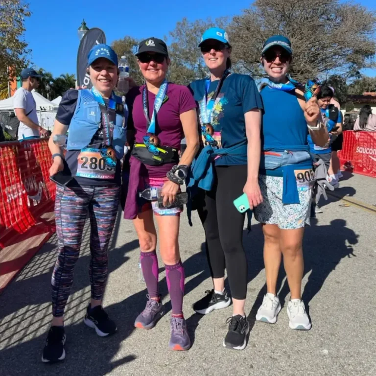 Four women smiling after completing a half marathon race